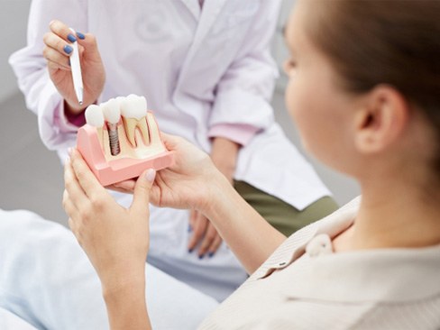 dentist showing a patient a model of how dental implants work in Garland 
