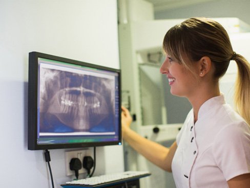 dental team member looking at X-rays from a patient