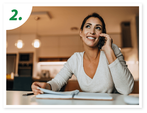 A woman in a cozy kitchen smiles while talking on the phone.