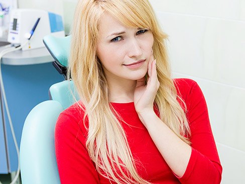 Woman in dental char holding cheek