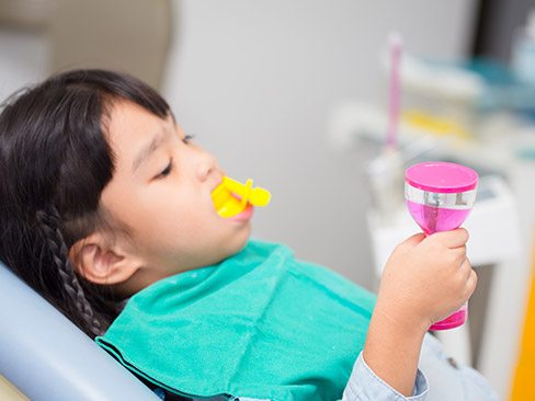 Child in dental chair receiving fluoride treatment