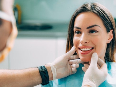 Cosmetic dentist in Garland looking at patient’s teeth 