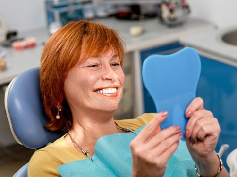 Older woman admiring her smile in hand mirror  