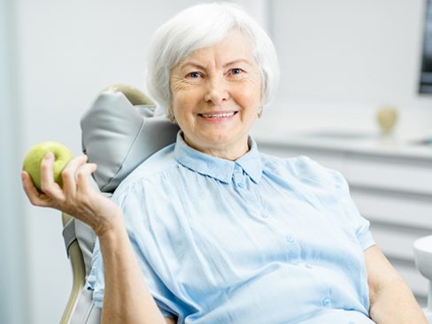 A woman with dentures holding an apple