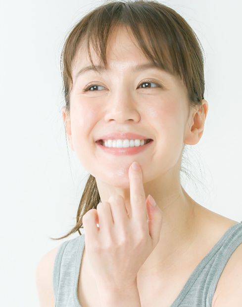 Woman pointing to smile after dental implant tooth replacement