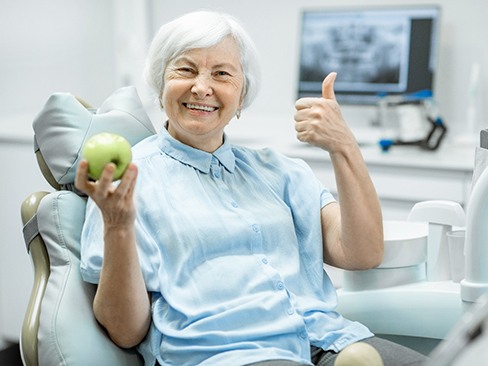 Woman with dental implants holding an apple