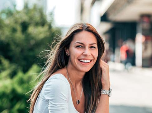 Woman with watch sitting outside after seeing emergency dentist in Garland, TX