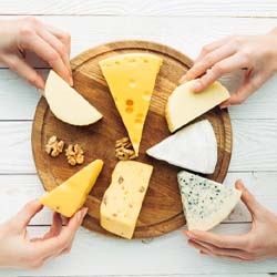 Several hands taking cheese off a tray