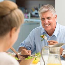 Older man with dental implants in Garland eating a meal