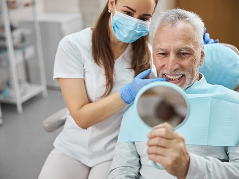 An elderly man admiring his new dental implants