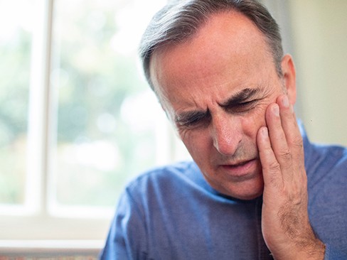 An older man having side effects from dental implant placement