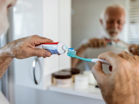 An older man putting toothpaste on his toothbrush