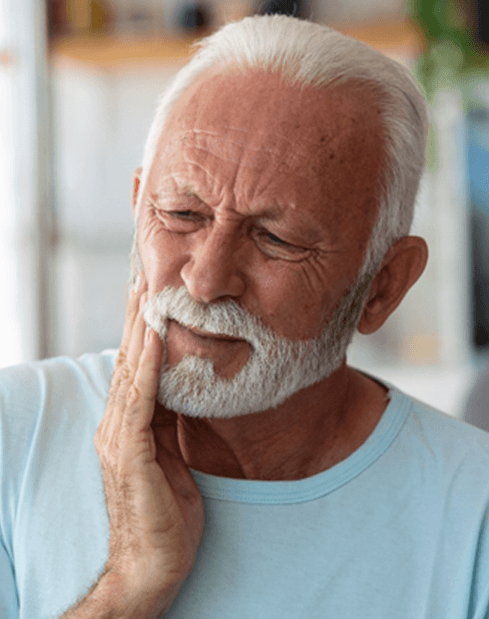 Man in light blue shirt with pain from failed dental implant in Garland, TX