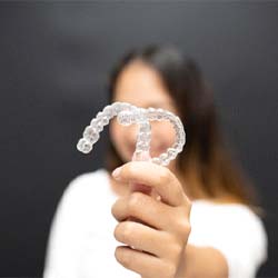 young woman holding two clear aligners