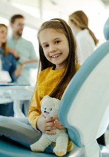 : Young girl in yellow shirt smiling in dentist’s chair