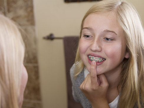 Young girl looking at her braces in the mirror