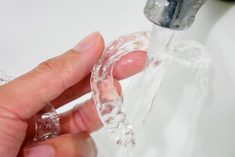 Invisalign aligner being rinsed under a sink