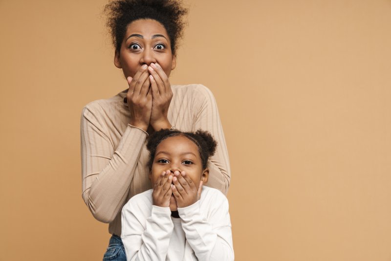 Child and parent covering their mouths after braces break