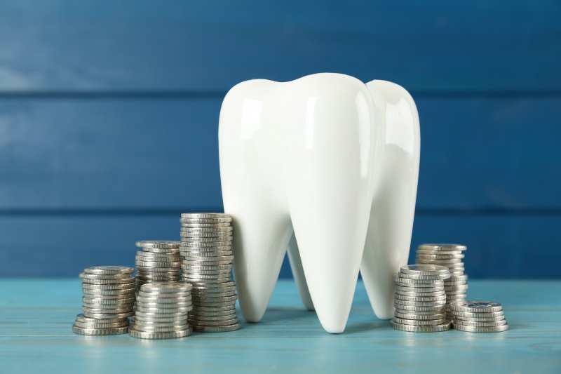 A large model tooth surrounded by stacks of silver coins